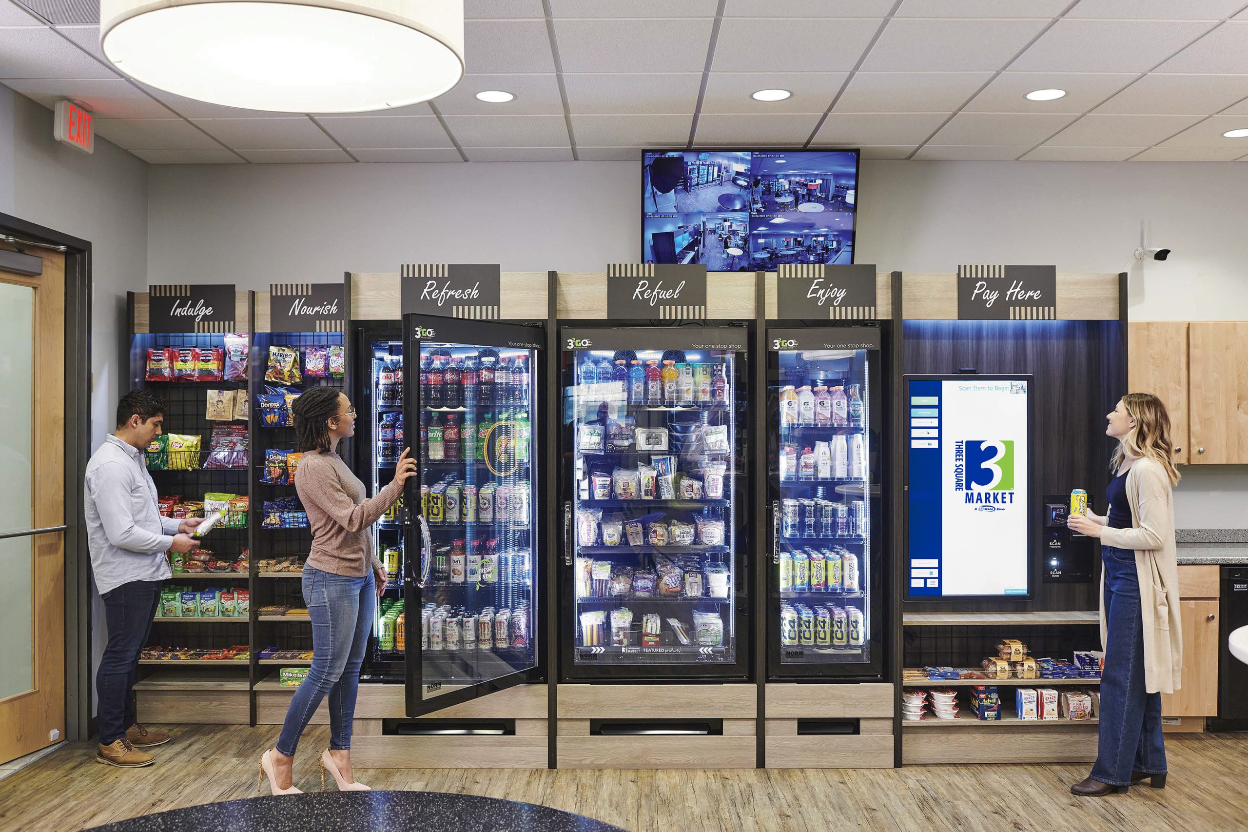 large screen with new logo a couple of people standing in front of a vending machine